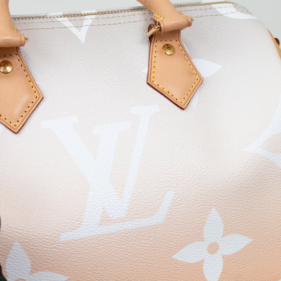 Designer handbag with beige handle and white monogram pattern on a light background