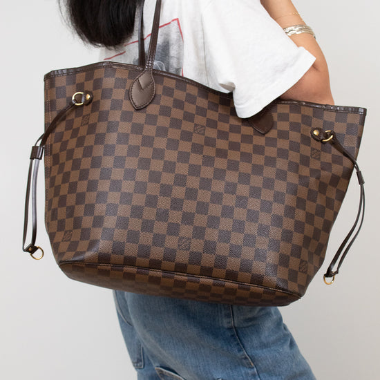Person holding a brown checkered handbag against a plain background