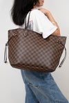 Person holding a brown checkered handbag against a plain background