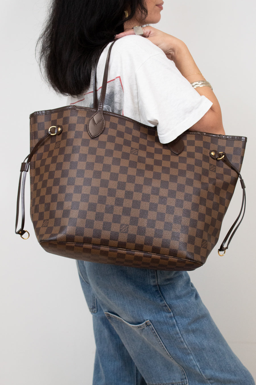 Person holding a brown checkered handbag against a plain background