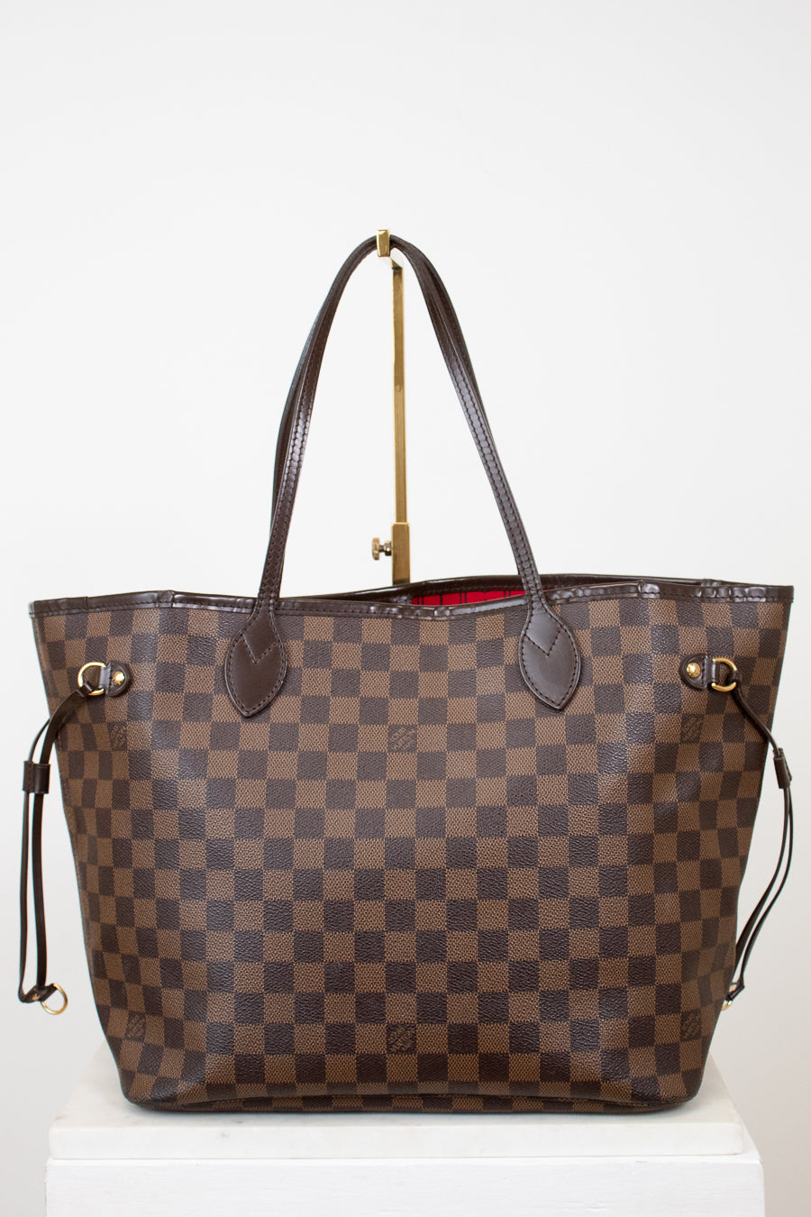 Brown checkered handbag with gold accents on a white background
