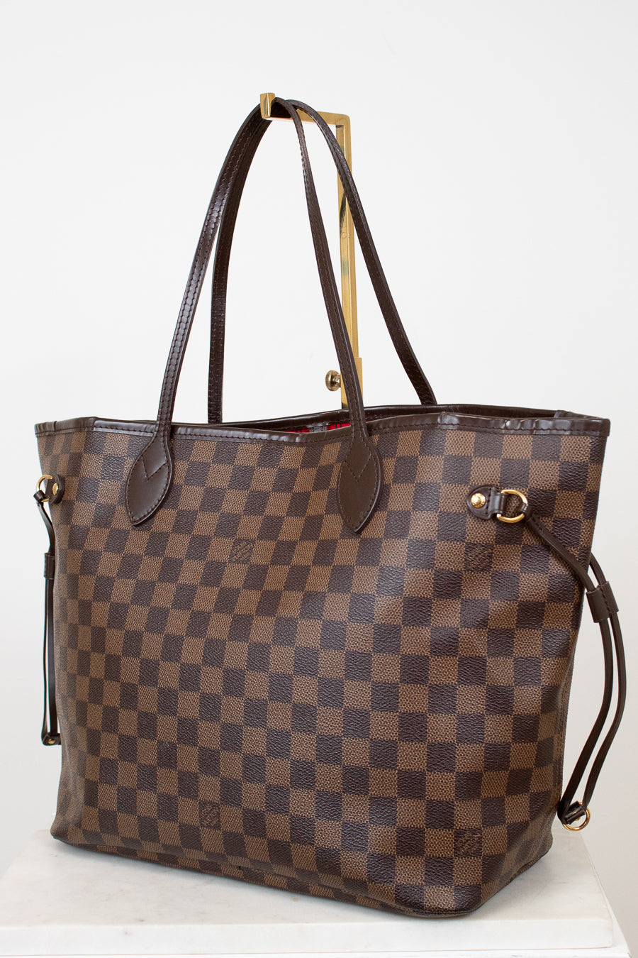 Brown checkered handbag with gold accents on a white background