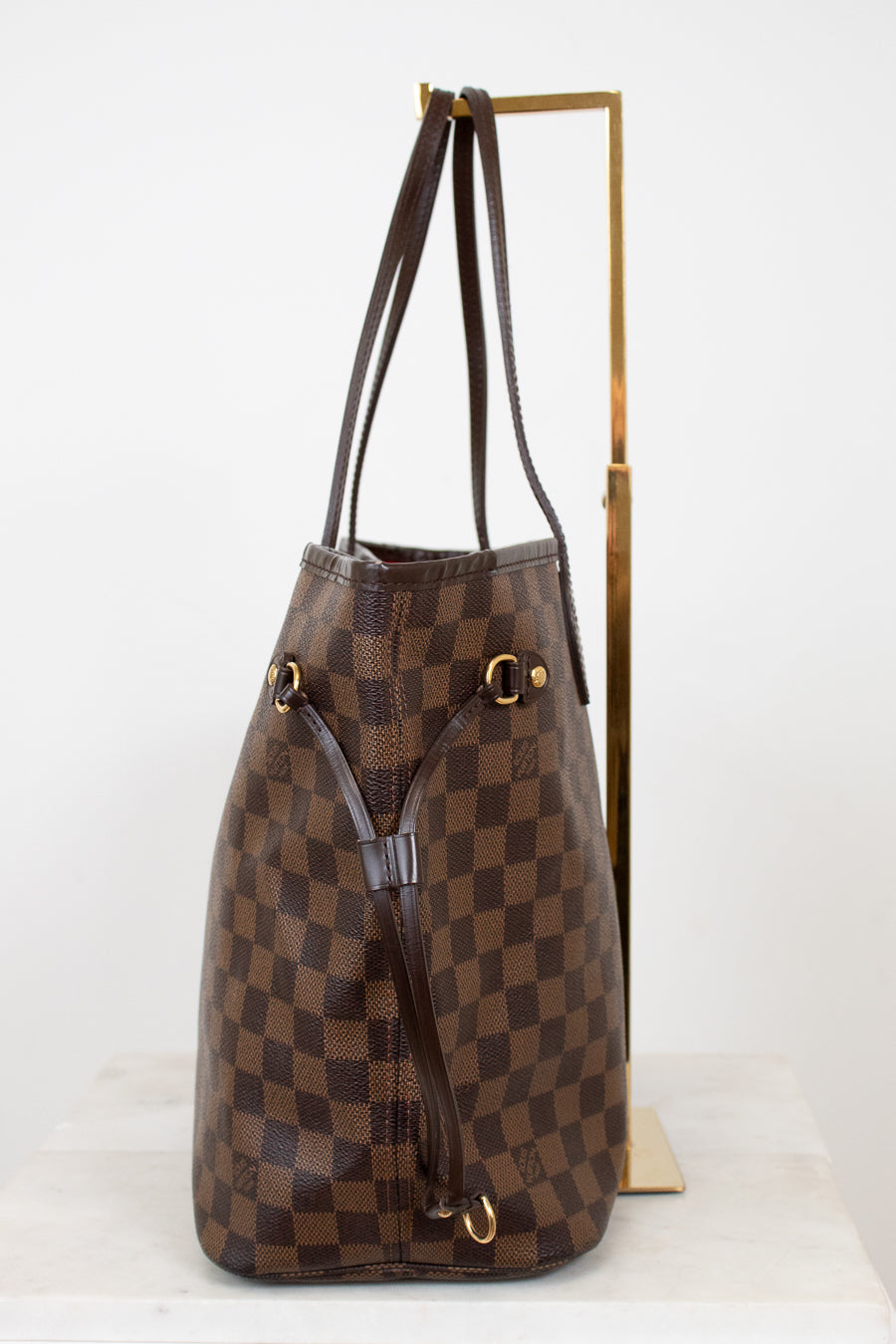 Brown checkered handbag with gold accents on a white background