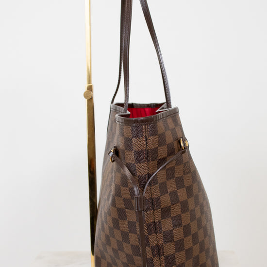 Brown checkered handbag with a gold handle on a white background