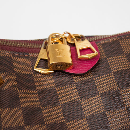 Designer handbag with gold locks and a pink tab on a white background