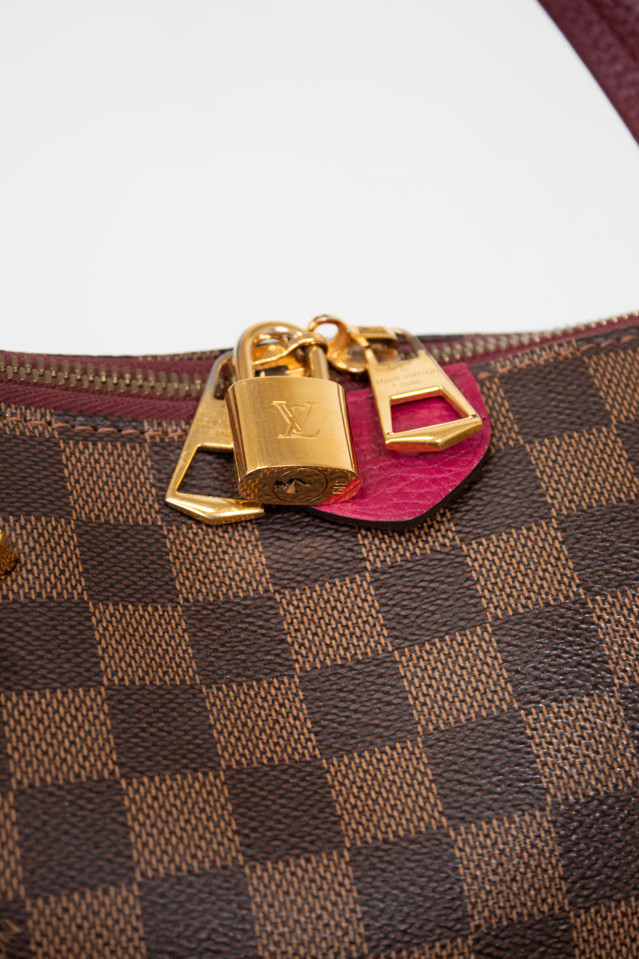 Designer handbag with gold locks and a pink tab on a white background