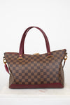Brown checkered handbag with red accents on a white background