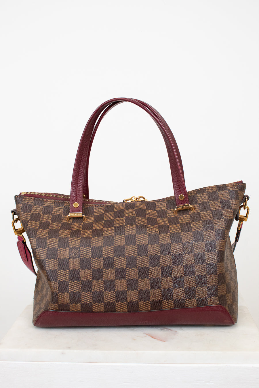Brown checkered handbag with red accents on a white background