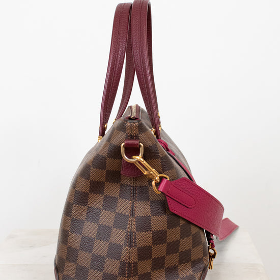 Designer handbag with brown checkered pattern and red strap on a white background