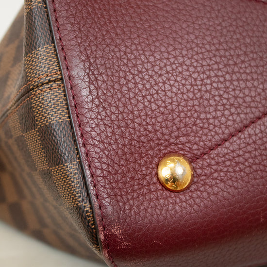 Close-up of a maroon leather handbag base with gold studs on a light background