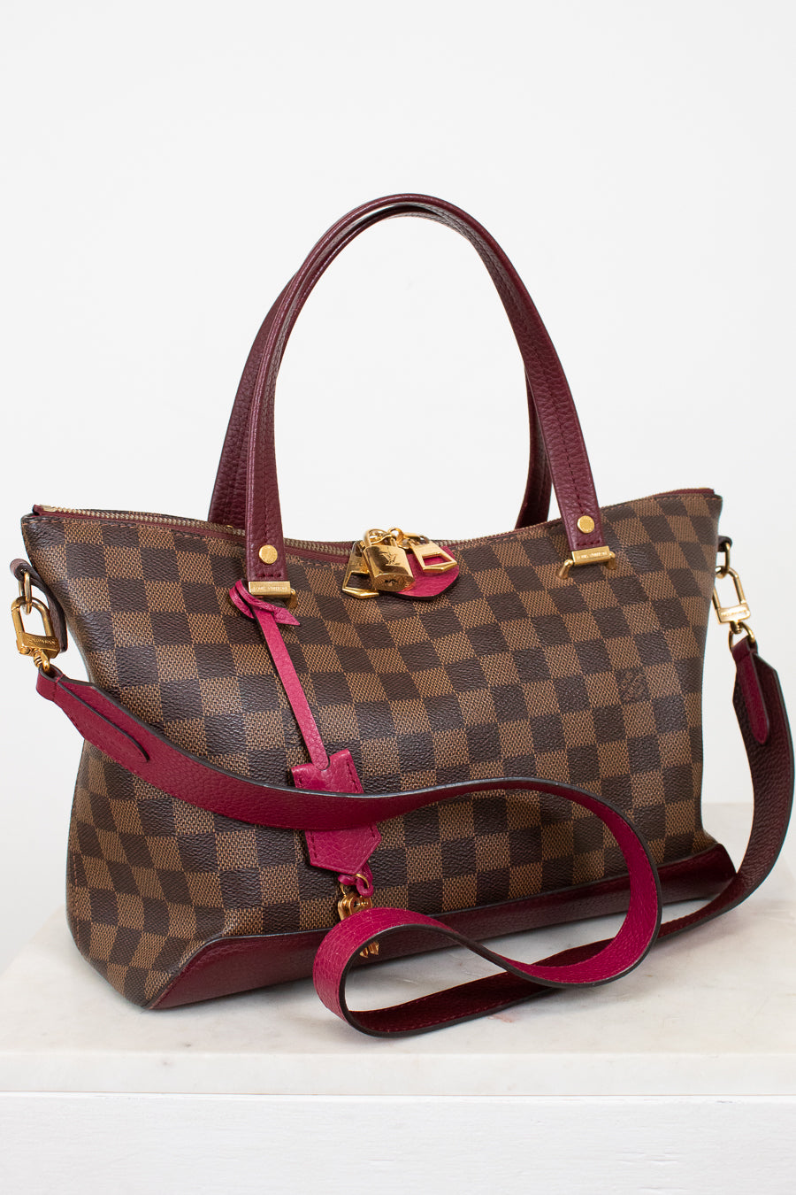 Designer handbag with checkered pattern and red accents on a white background