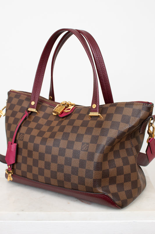 Brown checkered handbag with red accents on a white background