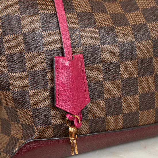 Designer handbag with a pink strap and gold hardware on a marble surface