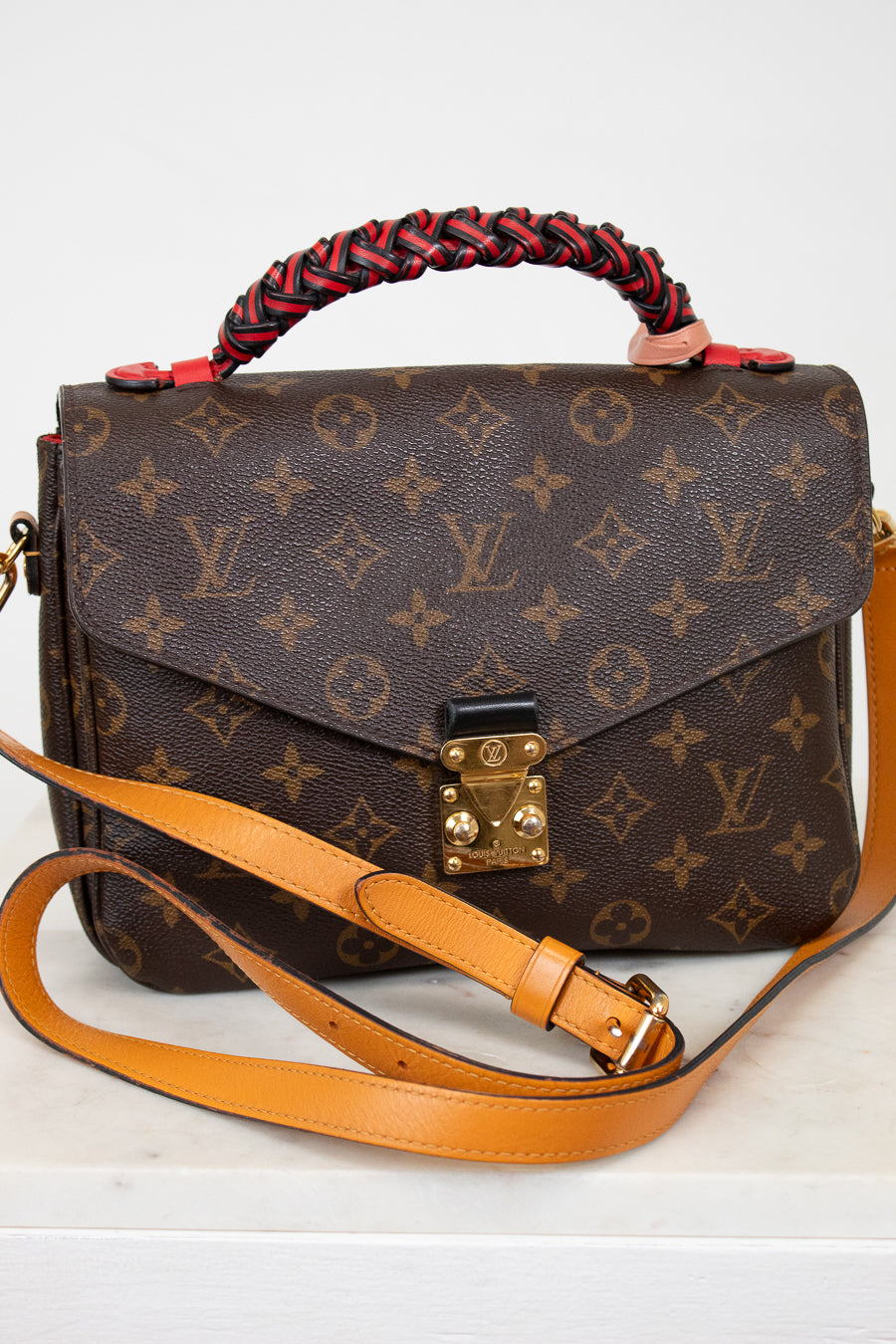 Designer handbag with monogram pattern on a white background