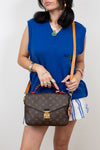 Woman holding a brown Louis Vuitton handbag against a white background