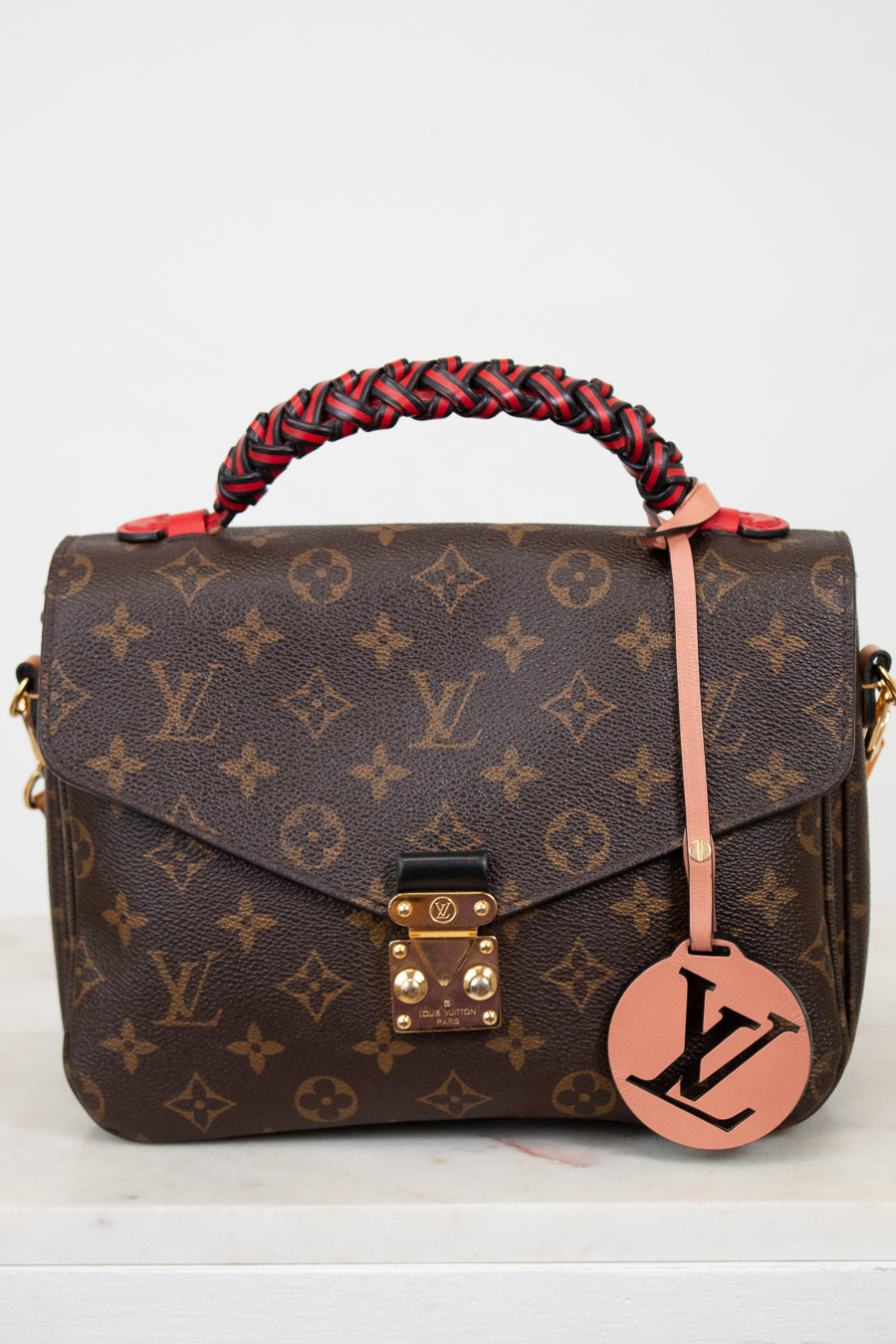 Designer handbag with monogram pattern on a white background