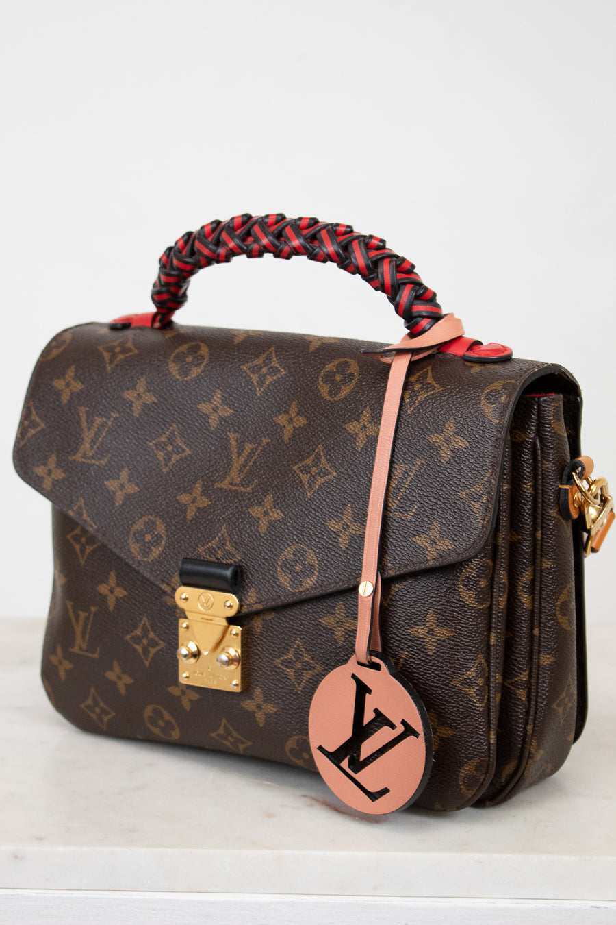 Designer handbag with monogram pattern on a white background