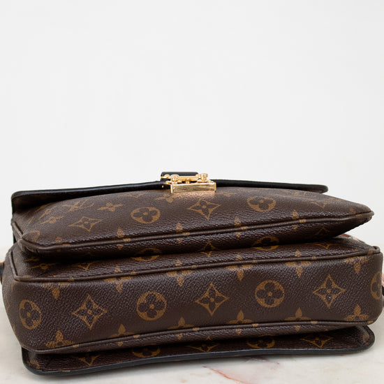 Brown monogram handbag with gold clasp on a white background