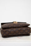 Brown monogram handbag with gold clasp on a white background