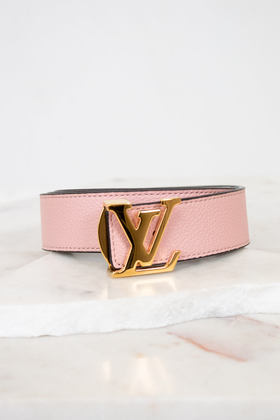 Pink belt with gold buckle on a white background