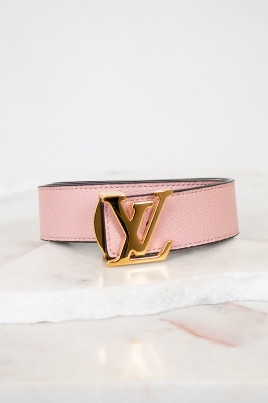 Pink belt with gold buckle on a white background