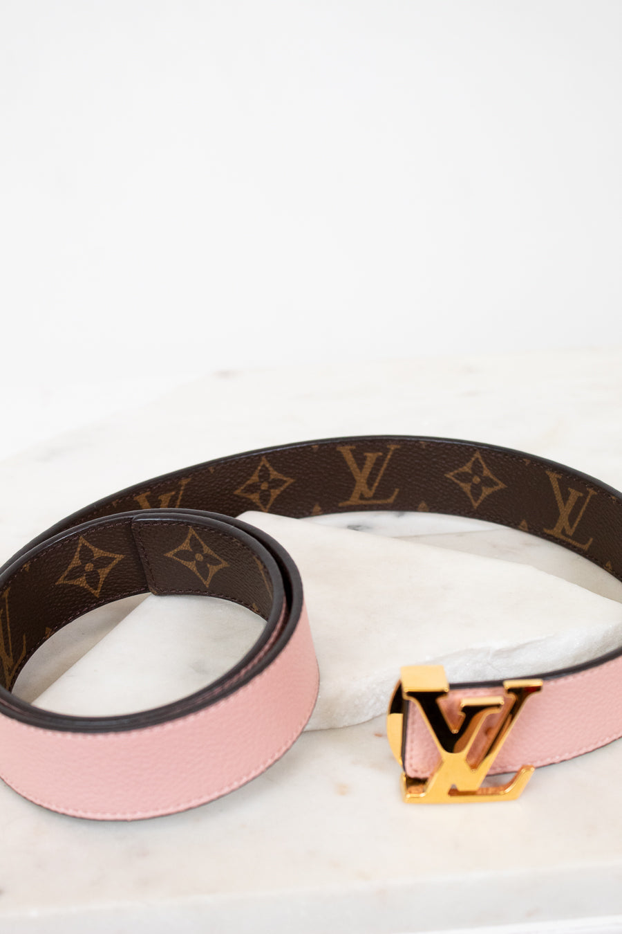 Louis Vuitton belt with pink strap and gold buckle on a white background
