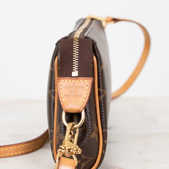 Close-up of a brown leather handbag with gold accents on a light background