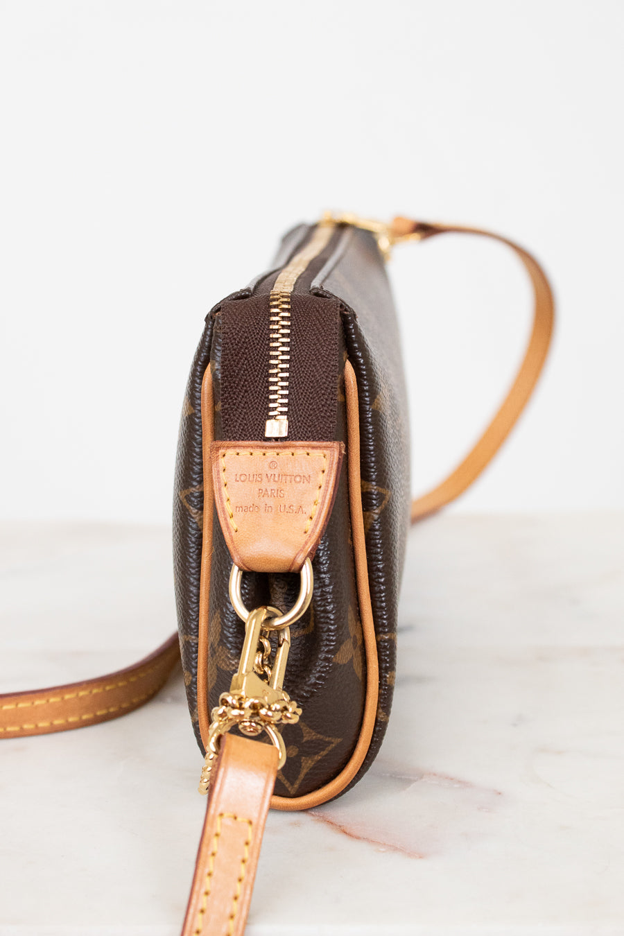 Close-up of a brown leather handbag with gold accents on a light background