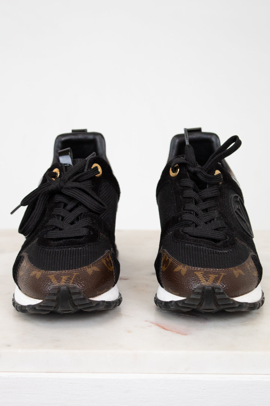 Black sneakers with brown monogram pattern on a white background