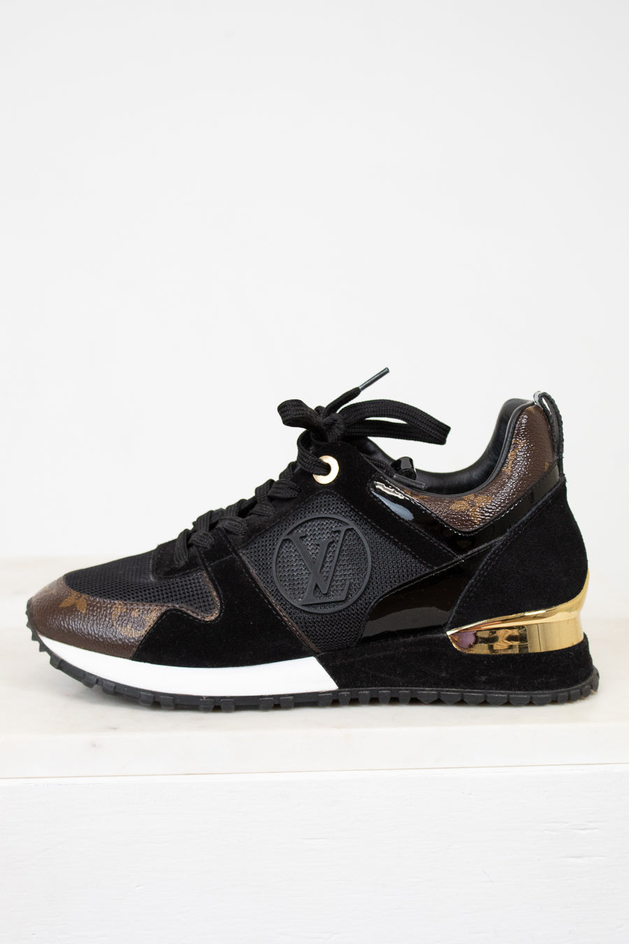 Black sneaker with gold accents on a white background