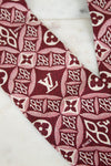 Close-up of a red and white patterned fabric with a logo on a marble surface