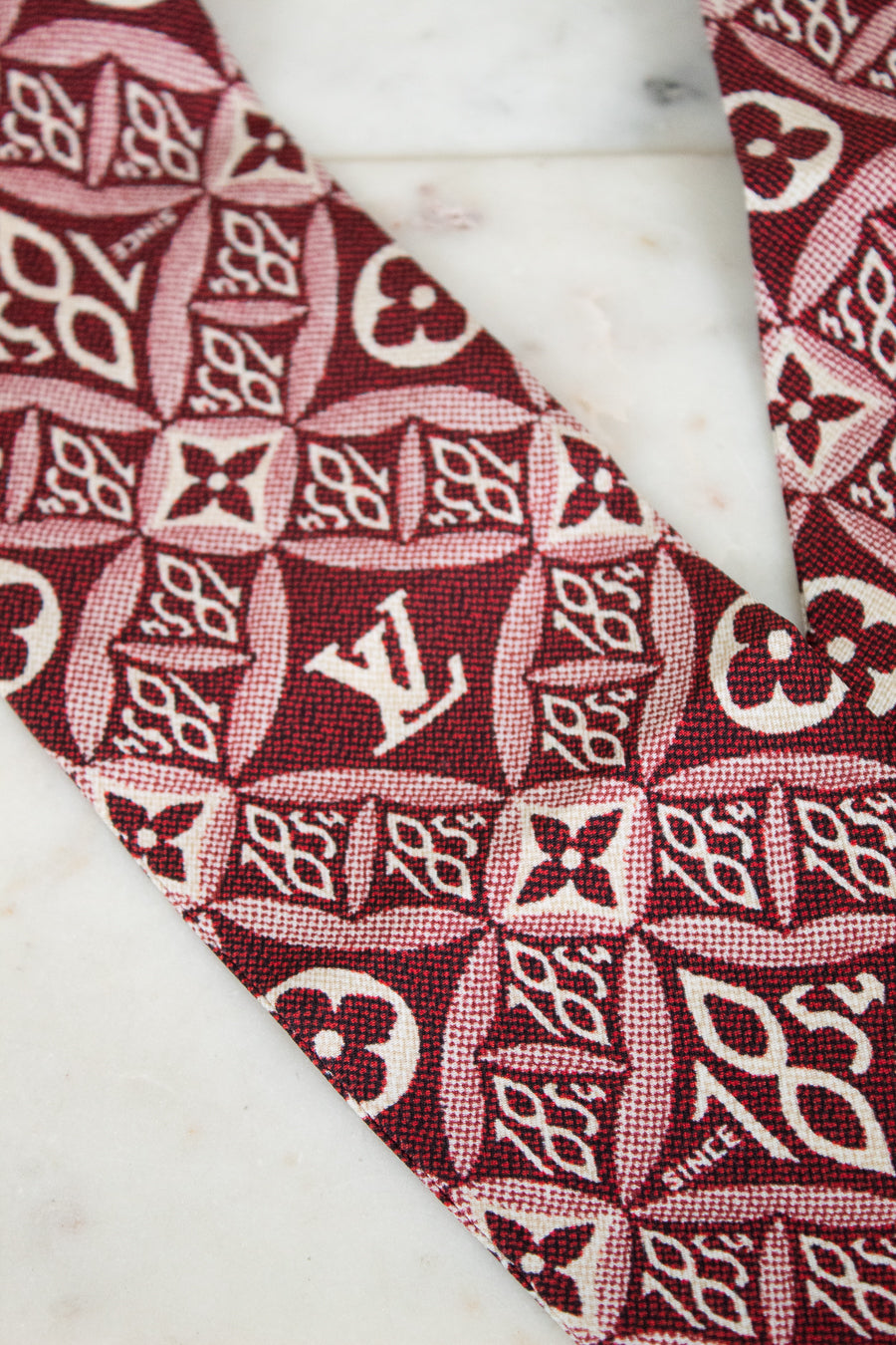 Close-up of a red and white patterned fabric with a logo on a marble surface