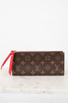 Louis Vuitton wallet with monogram pattern and red zipper on a white marble surface