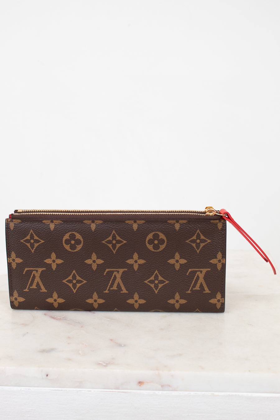 Louis Vuitton wallet with monogram pattern on a marble surface