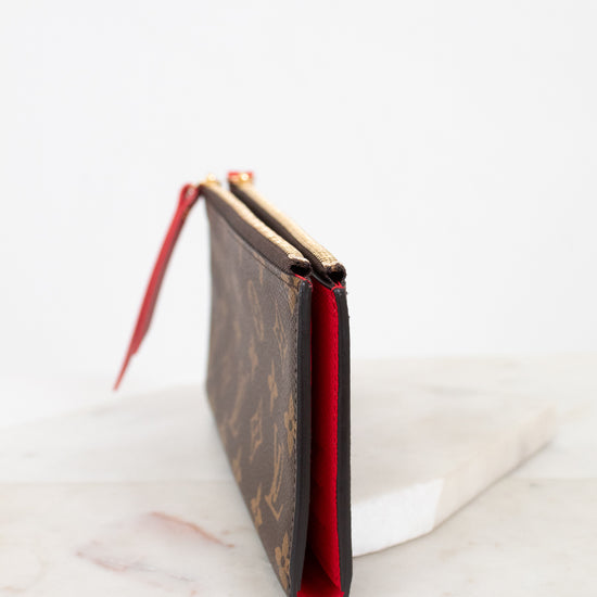 Side profile of Louis Vuitton wallet with red interior on a marble surface