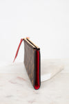 Side profile of Louis Vuitton wallet with red interior on a marble surface
