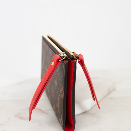 Louis Vuitton wallet with red interior and zipper details on a white surface