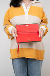 Person wearing a colorful striped shirt holding an open red wallet against a plain background