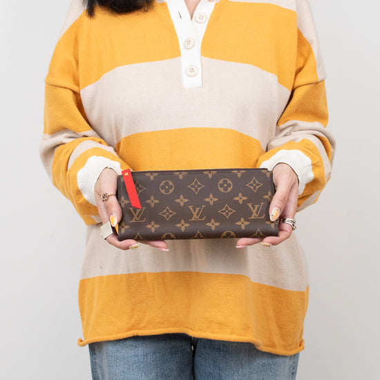 Person holding a Louis Vuitton wallet against a plain background