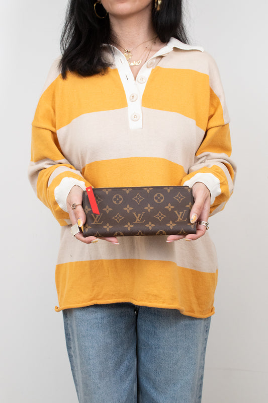 Person holding a Louis Vuitton wallet against a plain background