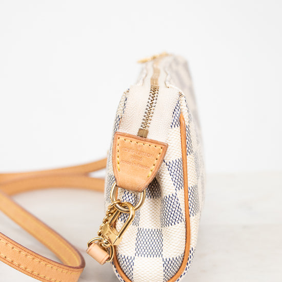 Small checkered handbag with beige strap on a light background