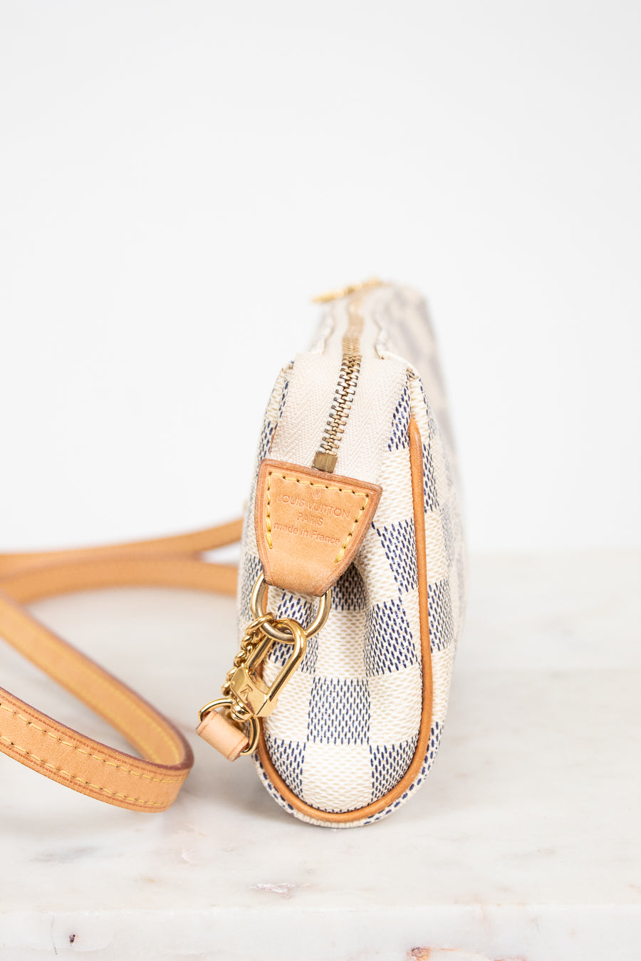 Small checkered handbag with beige strap on a light background