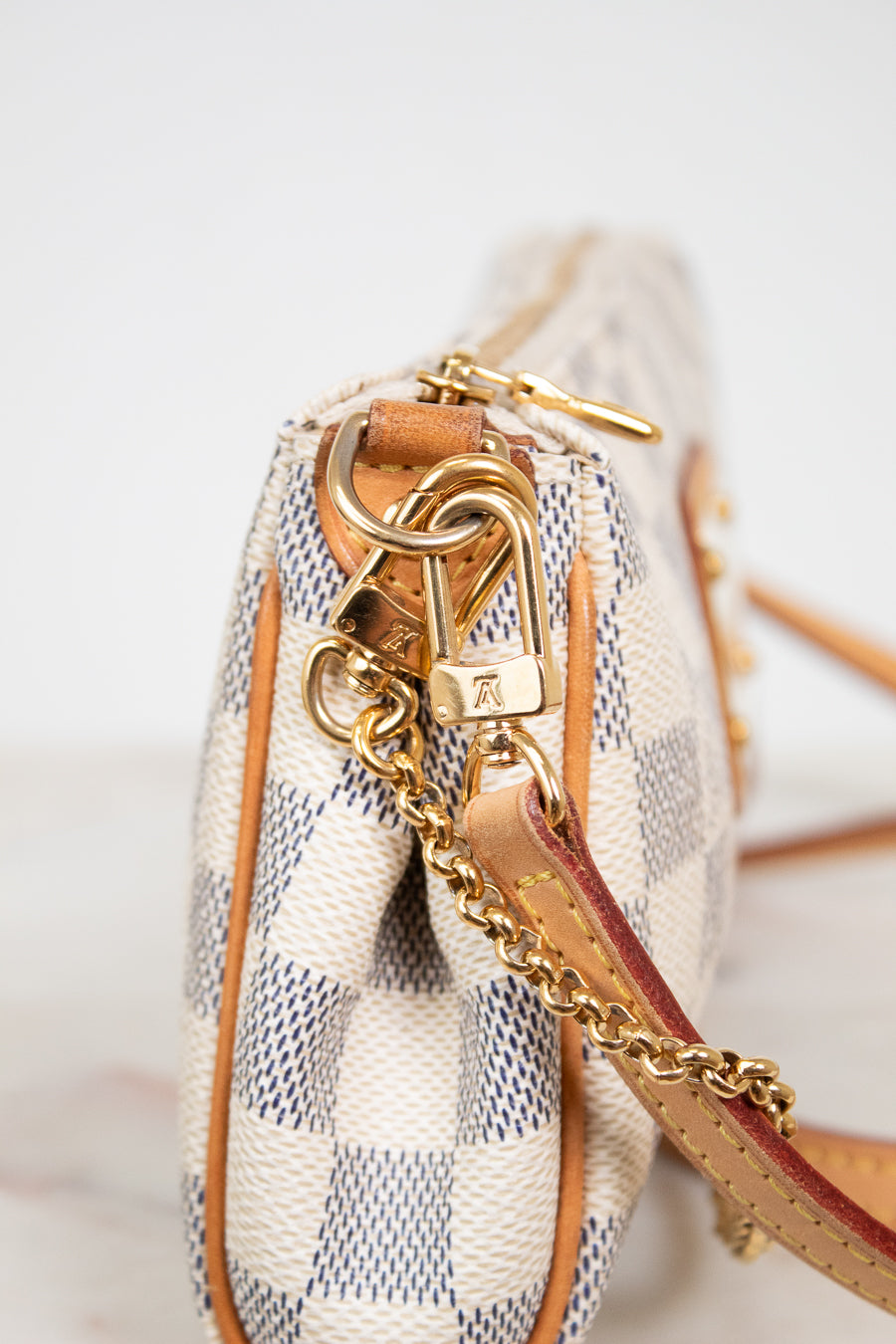Close-up of a checkered handbag with gold chain and strap on a light background