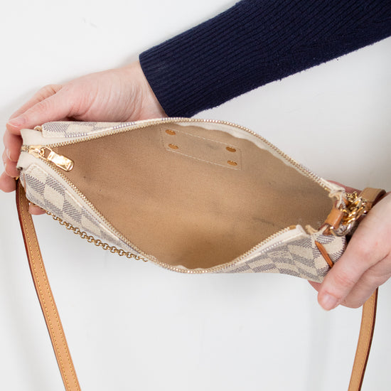 Person holding a beige handbag with a strap against a white background