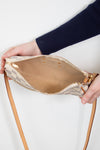 Person holding a beige handbag with a strap against a white background