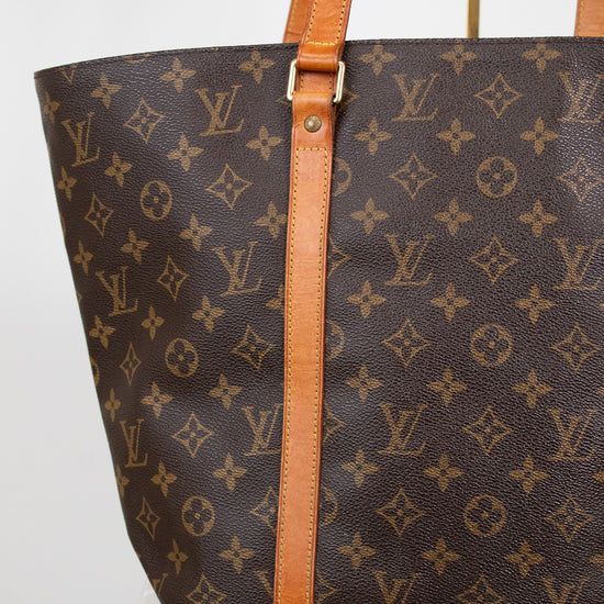 Louis Vuitton monogram handbag with brown leather straps on a white background