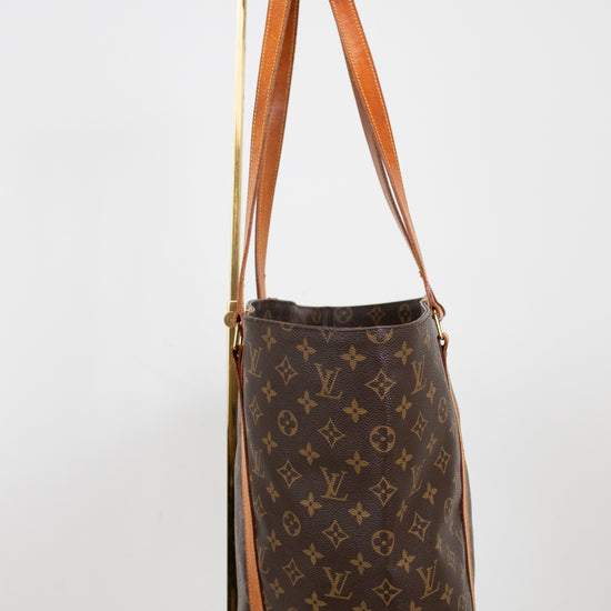 Brown monogram handbag with tan leather straps on a white background