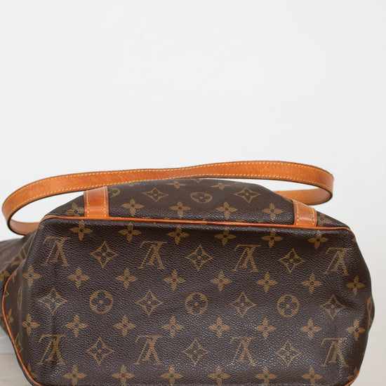 Brown monogram handbag with orange leather handles on a white background