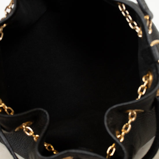 Close-up of the interior of a black leather bucket bag with gold-tone chain trim along the ruffled edge.
