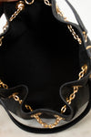 Close-up of the interior of a black leather bucket bag with gold-tone chain trim along the ruffled edge.